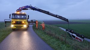 Auto op de kop naast dijk in Schagen
