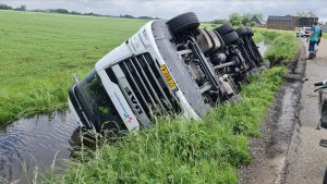 Gekantelde vrachtwagen languit in de sloot