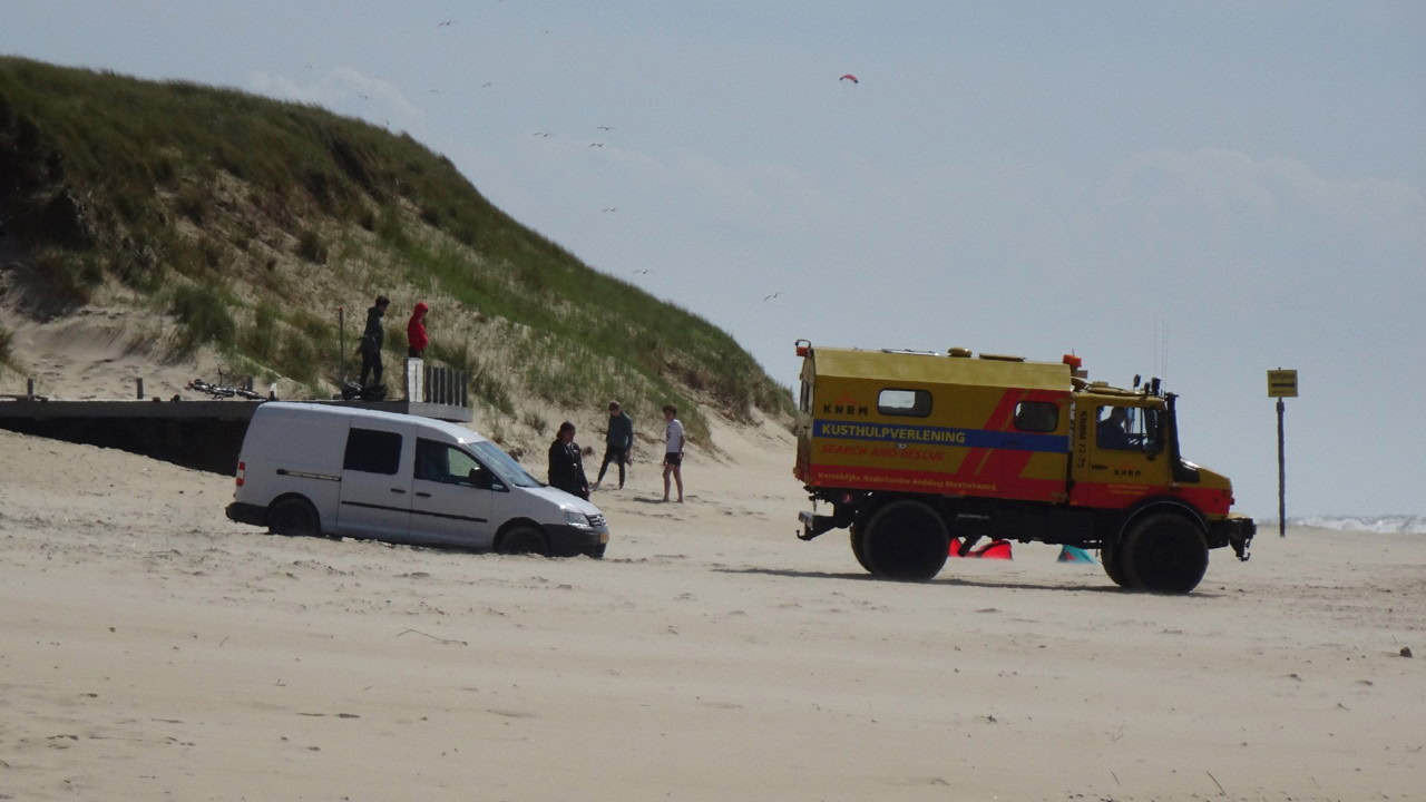 Kitesurfer met auto vast in het zand